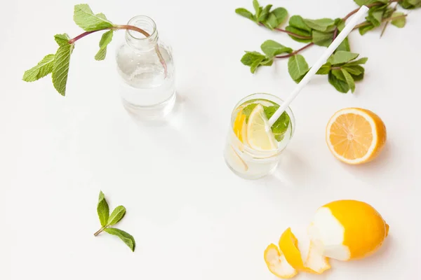 Limonada casera con agua, limón y hojas de menta en un vaso sobre un fondo blanco . —  Fotos de Stock