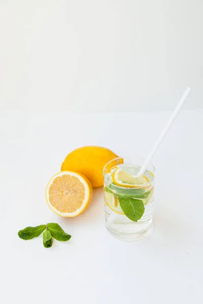 Limonada casera con agua, limón y hojas de menta en un vaso sobre un fondo blanco . —  Fotos de Stock