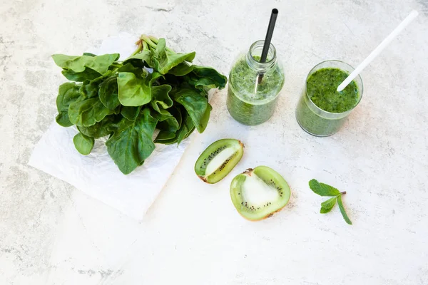 Cóctel verde en una botella y en un vaso con espinacas, menta, romero, kiwi y manzana sobre un fondo claro . —  Fotos de Stock