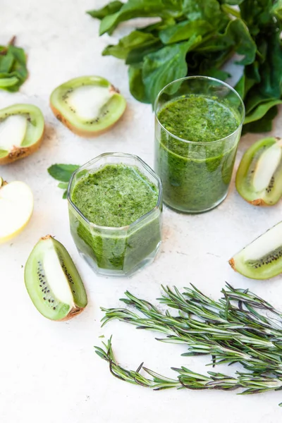 Cóctel verde en una botella y en un vaso con espinacas, menta, romero, kiwi y manzana sobre un fondo claro . — Foto de Stock