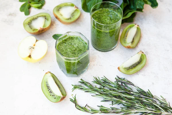 Cóctel verde en una botella y en un vaso con espinacas, menta, romero, kiwi y manzana sobre un fondo claro . —  Fotos de Stock