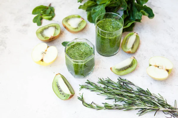 Cóctel verde en una botella y en un vaso con espinacas, menta, romero, kiwi y manzana sobre un fondo claro . —  Fotos de Stock