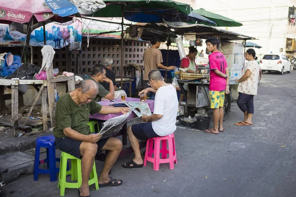 Bangkok, Thailand - June 28, 2015: Old men reading newspaper at a tea stall on Bangkok street