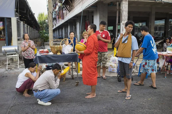 Bangkok, Thailand - June 28, 2015: People praying respect to monk on Bangkok street. Roughly 95 percent of the Thai people are practitioners of Theravada Buddhism, the official religion of Thailand