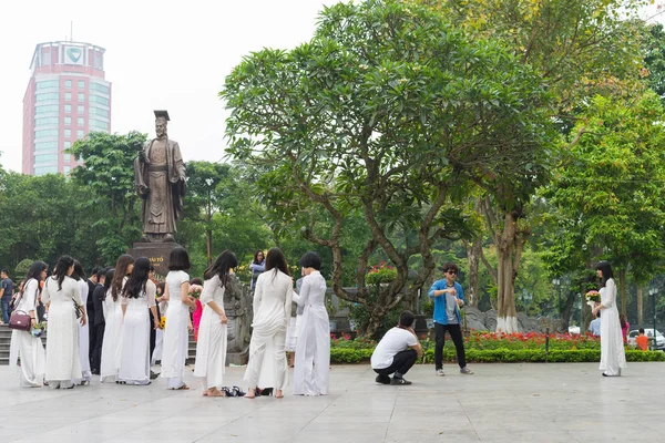 Hanoi, Vietnam - Apr 5, 2015: Group of students in Vietnamese traditional dress Ao Dai taking photo for memory at Ly Thai To park, Dinh Tien Hoang street, by Hoan Kiem lake