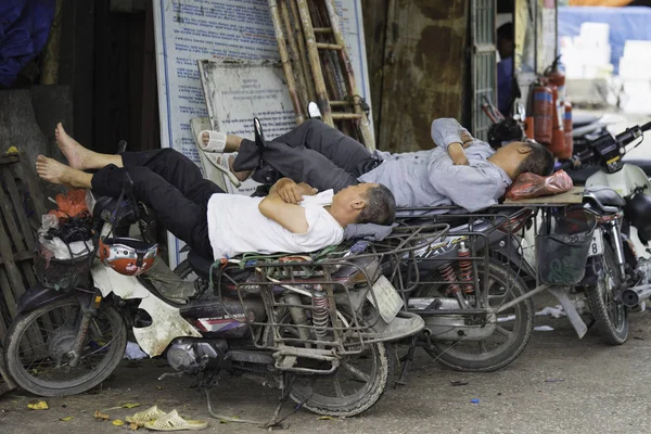 Hanoi, Vietnam - Aug 28, 2015: Motorcycle drivers sleep during lunch time at Long Bien market
