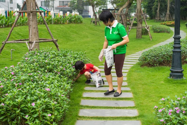 Hanoi, Vietnam - Apr 19, 2015: Family volunteers picking up litter in the park at Times City, a luxury and high class combination of apartment and mega mall retail center in Hanoi