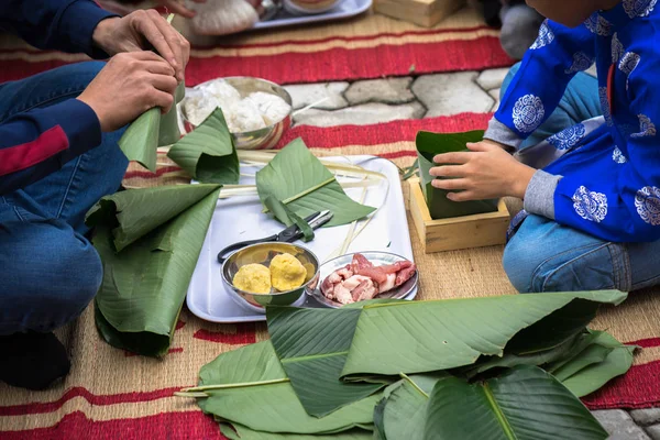 The son learning to make Chung cake by hands with his father closeup, Chung cake is the most important traditional Vietnamese lunar New Year (Tet) food.