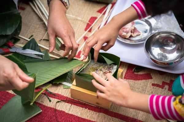 The daughter learning to make Chung cake by hands with his father closeup, Chung cake is the most important traditional Vietnamese lunar New Year (Tet) food.