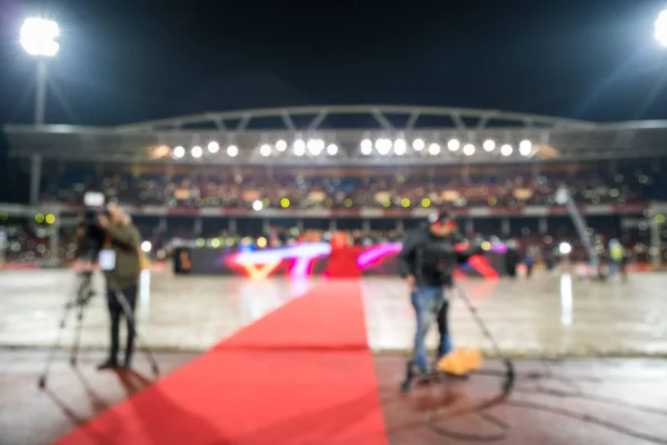 Blurred stadium with red carpet and video camera operator working at celebration event