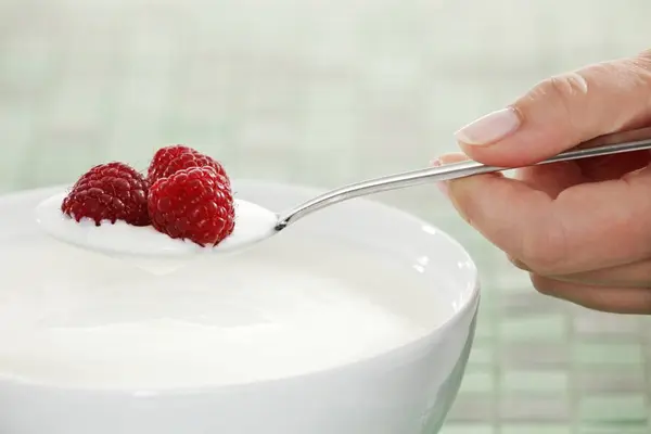Hand holding spoon with yogurt — Stock Photo, Image