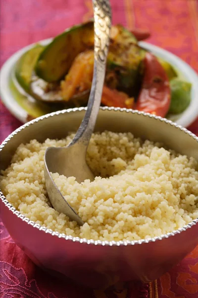 Couscous Tigela Prata Prato Legumes Atrás Superfície Vermelha — Fotografia de Stock