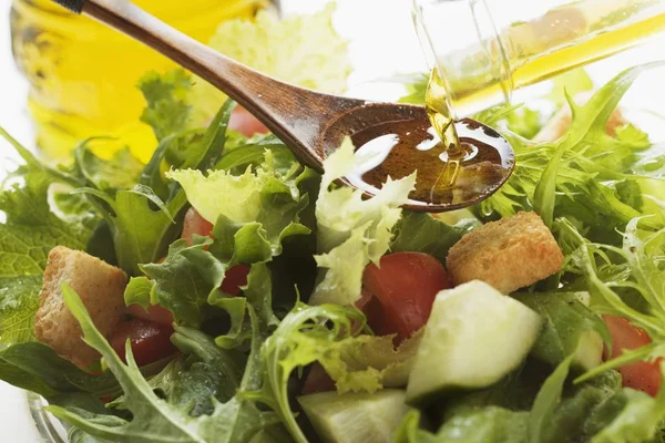Gieten olijfolie in salade — Stockfoto
