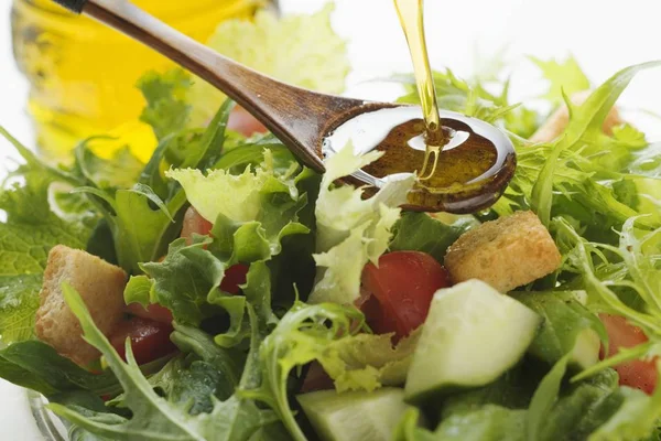 Pouring olive oil into salad — Stock Photo, Image