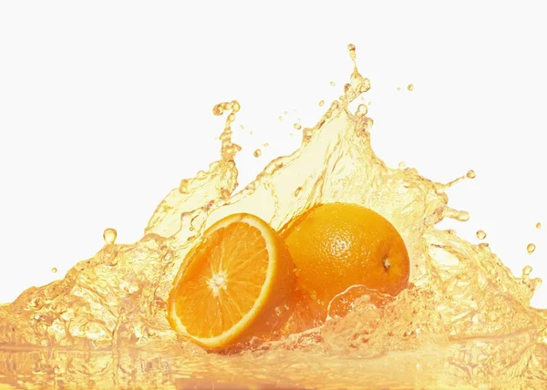 Laranjas com suco de laranja salpicante — Fotografia de Stock