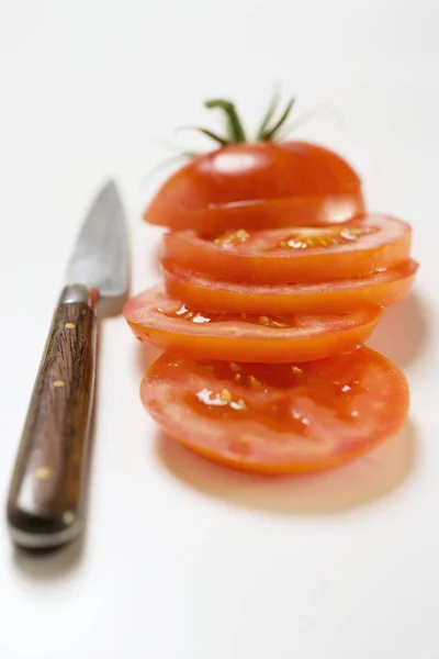 Порезанный помидор и нож — стоковое фото