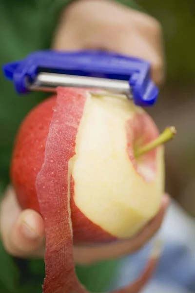 Enfant épluchage pomme rouge — Photo