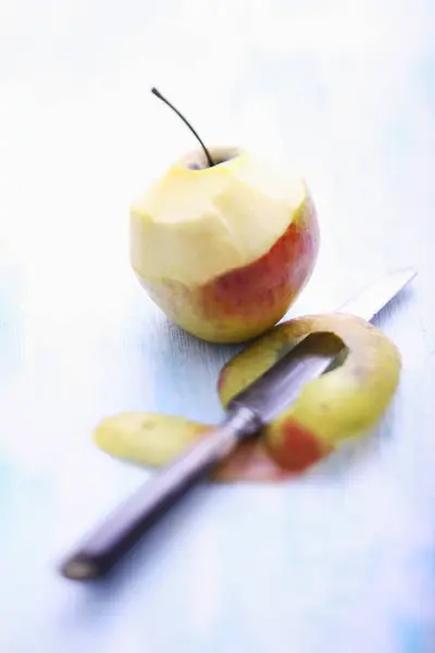 Half-peeled apple with knife — Stock Photo, Image