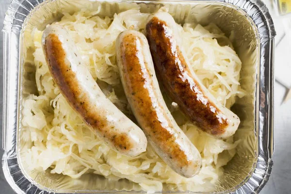Sausages with sauerkraut in aluminium container — Stock Photo, Image