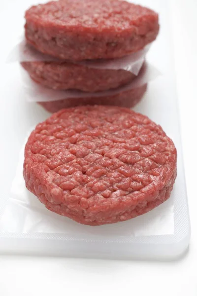 Raw burgers on white board — Stock Photo, Image