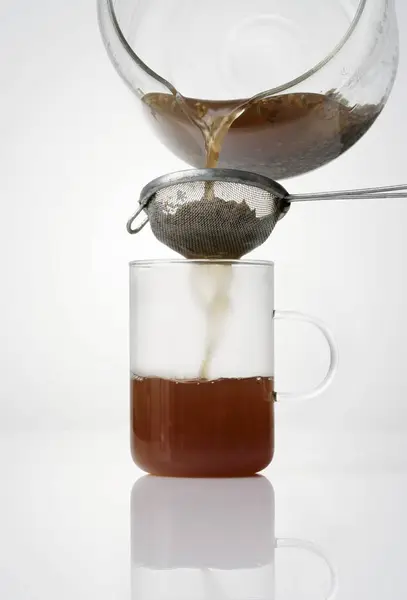 Overbelasting van de thee door een zeef — Stockfoto