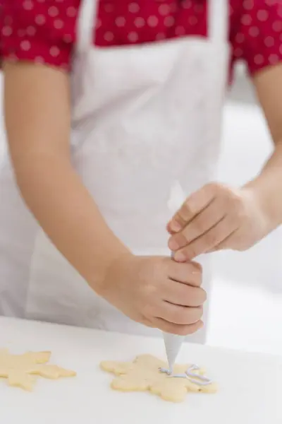 Child decorating sweet Christmas biscuit — Stock Photo, Image