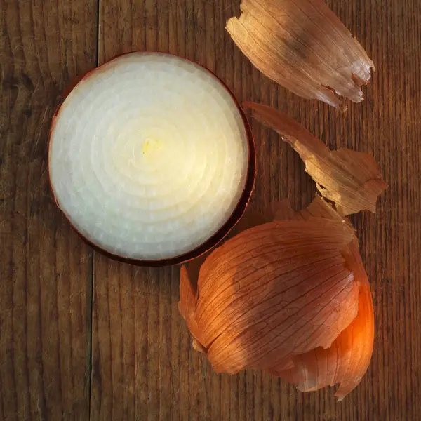 Onion with skin on wooden surface — Stock Photo, Image