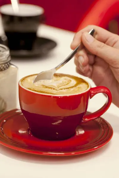 Hand stirring a hot cappuccino — Stock Photo, Image