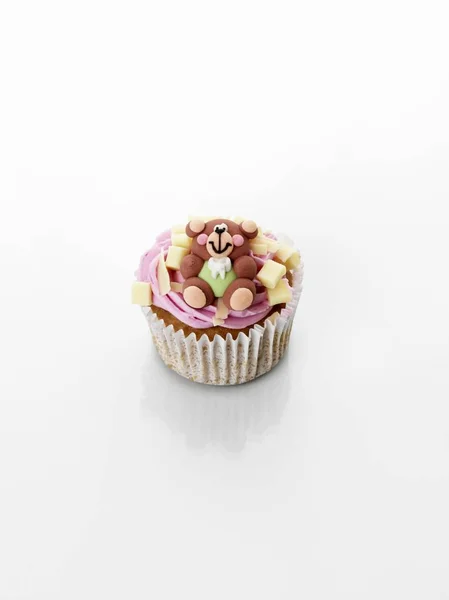 Cupcake decorated with cream and teddy bear — Stock Photo, Image