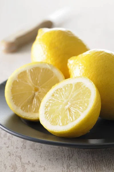 Fresh lemons with halves in plate — Stock Photo, Image