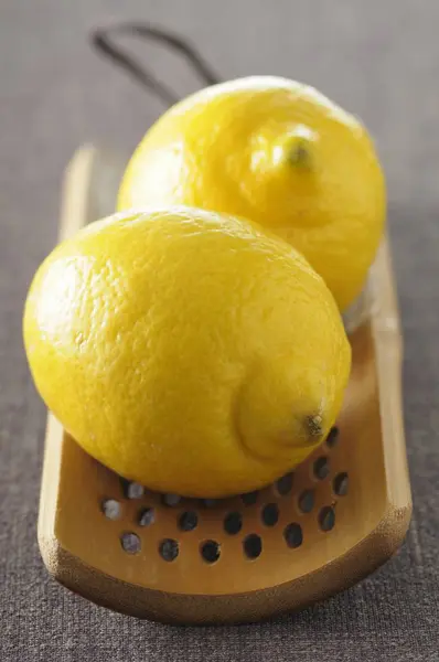 Fresh lemons on wooden grater — Stock Photo, Image