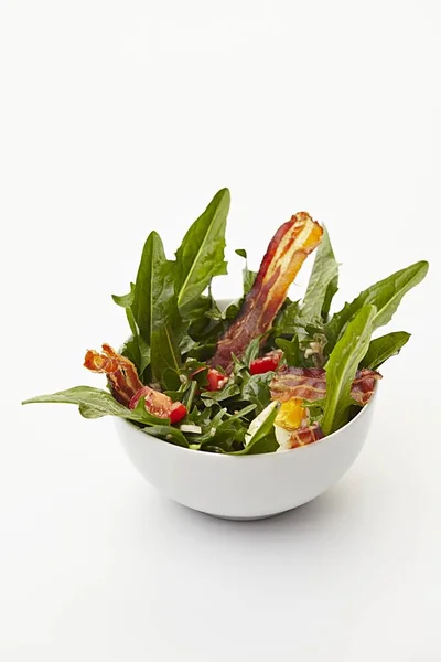Dandelion salad with tomatoes and fried bacon — Stock Photo, Image