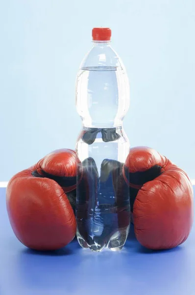 ミネラルウォーターのボトルとボクシング グローブのペアのクローズ アップ ビュー — ストック写真