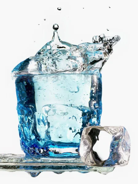 Ледяной куб падает в стакан воды — стоковое фото