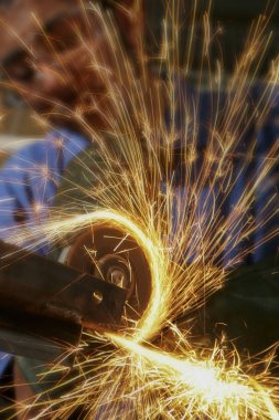 Metalworker bir açı değirmeni ile metal kesme.
