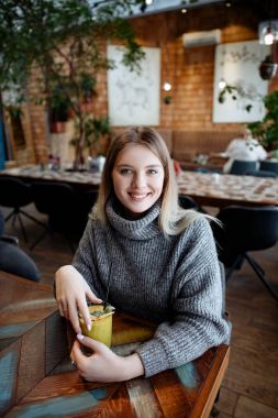 Kışın rahat bir kazak kafede oturur ve lezzetli yararlı berry smuz içecekler gri sarışın güzel kız.