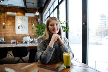 Kışın rahat bir kazak kafede oturur ve lezzetli yararlı berry smuz içecekler gri sarışın güzel kız.