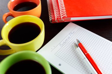 Kahveyle, defter, sketchbook ve iki koyu kahverengi ahşap masa üzerinde kalem planlama iş