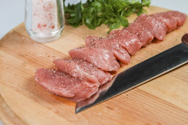 Мясо из свинины на разделочной доске готово к приготовлению свиной вырезки, разрезанной на куски медальонов — стоковое фото