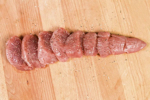 Мясо из свинины на разделочной доске готово к приготовлению свиной вырезки, разрезанной на куски медальонов — стоковое фото
