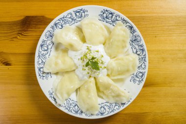 Ahşap masa üzerinde peynir ve crème fraiche ile haşlanmış mantı