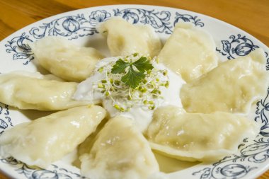 Ahşap masa üzerinde peynir ve crème fraiche ile haşlanmış mantı