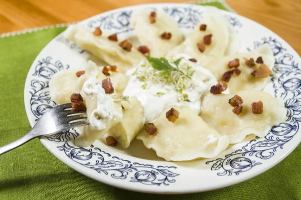 Bolinhos de massa cozidos com risca de porco de queijo e creme fraiche na mesa de madeira — Fotografia de Stock