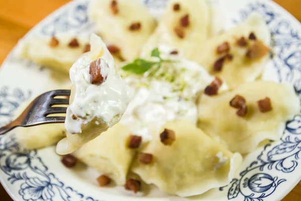 Bolinhos de massa cozidos com risca de porco de queijo e creme fraiche na mesa de madeira — Fotografia de Stock