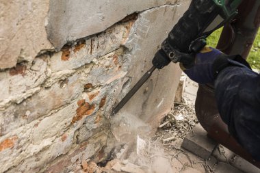 İşçi elektrik çekiç temizlik ile kırmızı tuğla duvar