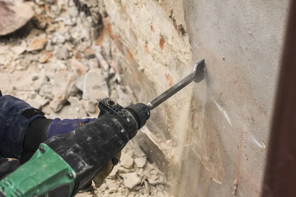 Arbeiter mit Elektrohammer putzt rote Ziegelwand — Stockfoto