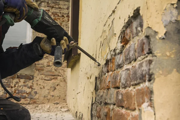 Arbeiter mit Elektrohammer putzt rote Ziegelwand — Stockfoto