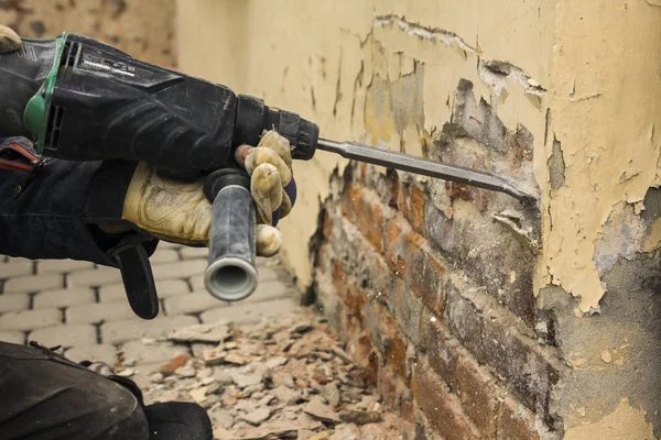 Arbeiter mit Elektrohammer putzt rote Ziegelwand — Stockfoto