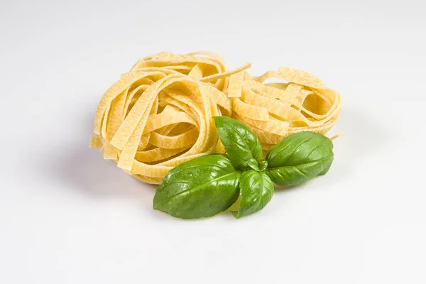 Tagliatelle crude e crude con foglie di basilico — Foto Stock