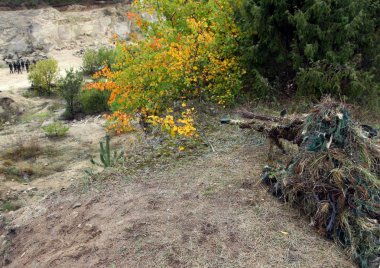 Avcı kamuflaj veya hedefleyen kamuflaj sonbahar arka plan çalılıklarda saklanarak asker. Keskin nişancı tüfeği ile.